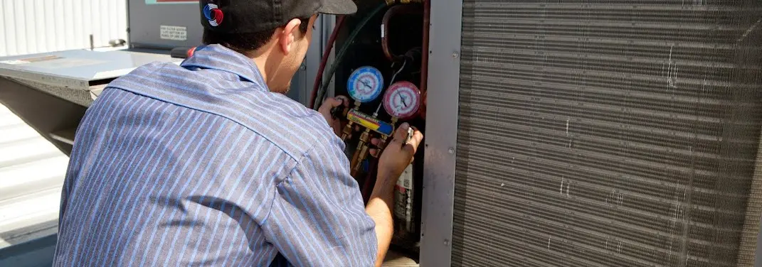 HVAC technician servicing a condenser unit in Holly Springs